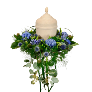 En urna av beige keramik är omgiven av en krans av blå blommor och gröna blad.